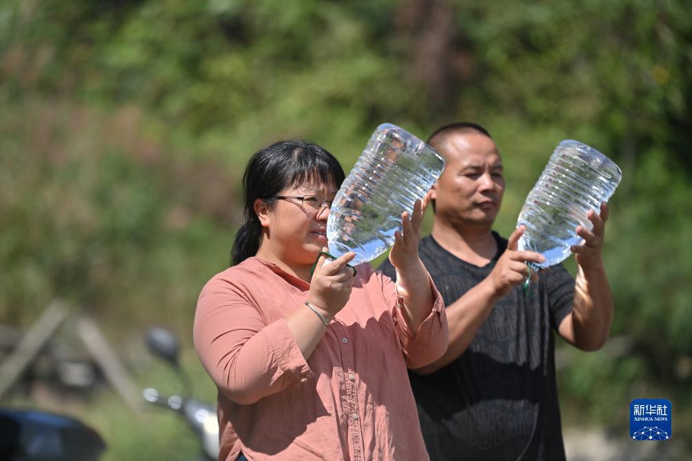 楊寧（左）在查看村民剛剛采集的水樣，為山泉水引水工程做準(zhǔn)備（10月8日攝）。新華社記者 黃孝邦 攝